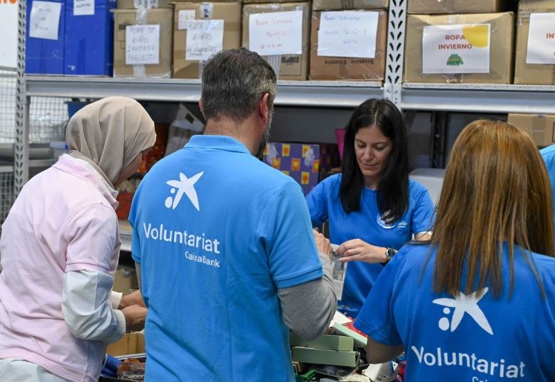 Un grupo de voluntarios CaixaBank con el distintivo polo azul prepara alimentos