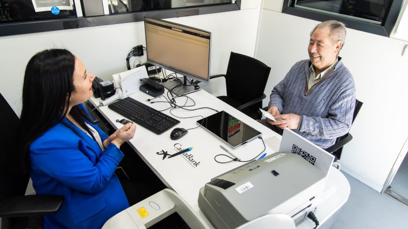 Atenci&oacute;n personalizada en una oficina m&oacute;vil de CaixaBank, con un cliente y un gestor sentados frente a un escritorio