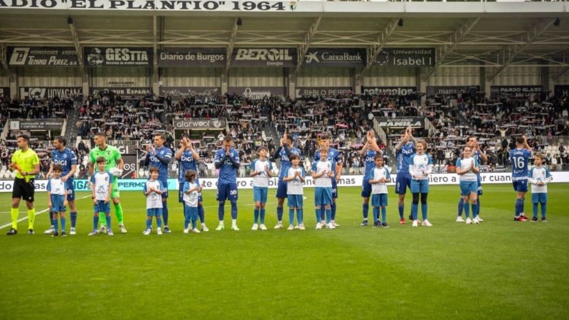 Ni&ntilde;os participantes en la convocatoria de Escort Kids en Burgos junto con los futbolistas en el terreno de juego.