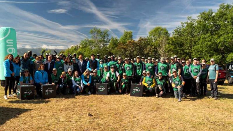 Grupo numeroso de voluntariado con camisetas verdes posa al aire libre, en terreno seco con &aacute;rboles y cielo despejado; pancartas y bander&iacute;n &ldquo;imagin&rdquo;, actividad de prevenci&oacute;n de incendios