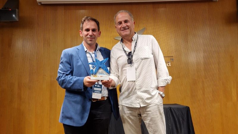 Dos hombres posan con el premio EmprendeXXI en un sal&oacute;n de actos.