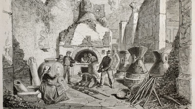 El pan reflejaba muy bien las desigualdades sociales e identifica el estatus de cada ciudadano Grabado antiguo de un taller de panadería con horno de leña, varias personas trabajando la masa y utensilios alrededor en un patio con muros en ruinas