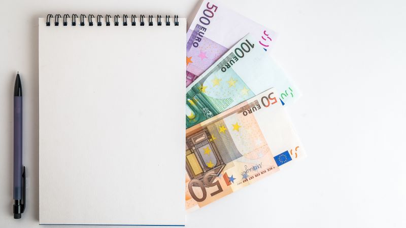 Bloc de notas con un bol&iacute;grafo gris y billetes de euro