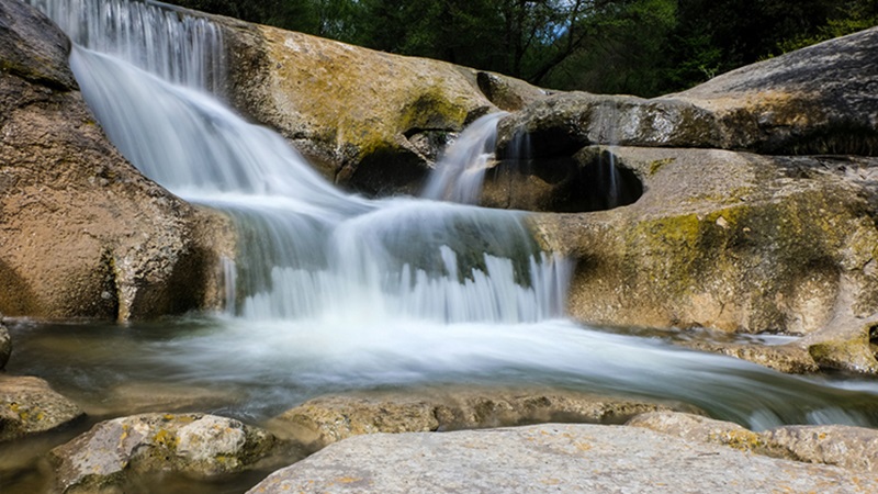 Una cascada cubre las rocas y desemboca en un lago en la Ruta del Salt de Sallent (Barcelona)